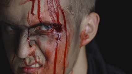 Halloween man portrait. Guy with dripping blood on his face. Scary makeup