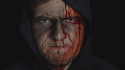 Man executioner Halloween makeup and costume. Guy with blood on his face