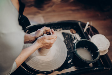 master makes a vase of clay, clay circle, close-up hands, mug of raw clay, hands made