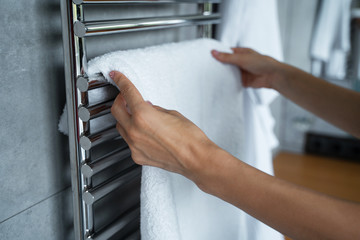 Female hands hanging a towel on the towel dryer