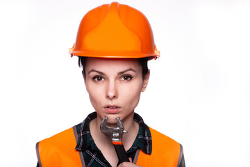 beautiful young girl worker in a helmet holds in her hand a wrench