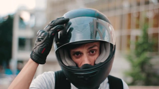 portrait of young attractive motorcyclist with black helmet on street. Man motorcycle biker
