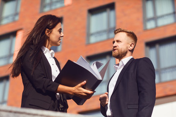 Businesspeople discuss documents on the background of a business building.