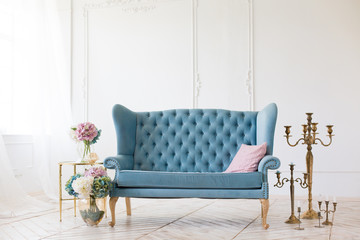 Blue soft sofa in light interior with fabric upholstery