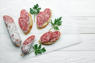 Italian sausage salami with white mold served with parsley on white wood background. 