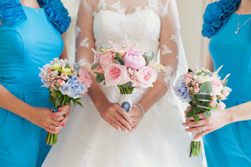 Bride and her friends with the same bouquets in their hands. Pink and blue colors. Closeup