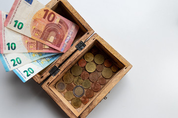 Euro-Scheinen und Euro-Münzen in einer offenen Schatztruhe aus Holz zeigen Reichtum, Finanzmanagement, Prämien, passives Einkommen, Sparsamkeit und finanzielle Sicherheit