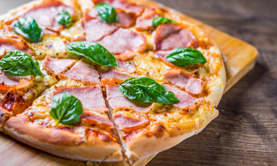Pizza with Mozzarella cheese, ham, tomato sauce, pepper, Spices and Fresh basil. Italian pizza on wooden table background