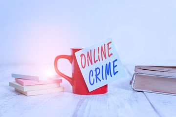 Text sign showing Online Crime. Business photo text crime or illegal online activity committed on the Internet Coffee cup blank sticky note stacked note pads books retro old wooden table