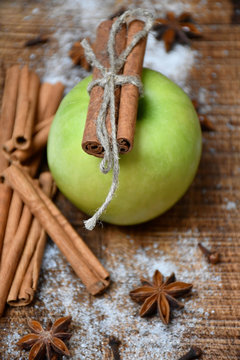 An apple, cinnamon sticks, star-anise, cloves and snow
