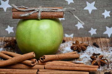 An apple, cinnamon sticks, star-anise, cloves and snow