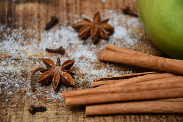 An apple, group of cinnamon sticks, star-anise, cloves and snow