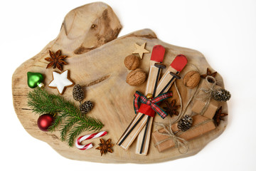 Top view: a fir / spruce twig /tree branch, gifts, nuts, a candy cane, toy skis, four cones, a star-shaped cookie, star-anise, a star & Christmas-tree decorations