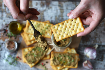 Male hands put the home liver pate on a cracker with a fork. Delicious homemade pate with spices and herbs. Keto diet. Healthy food. Selective focus. Macro.
