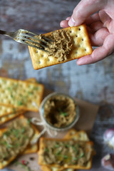 Male hands put the home liver pate on a cracker with a fork. Delicious homemade pate with spices...
