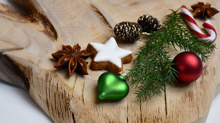 A natural green fir tree branch, a star-shaped cookie, a star-anise, cones, candy canes & Christmas-tree decorations (ball & a heart)