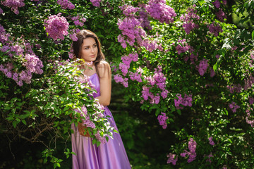 Beauty Romantic woman in flowers. Sensual Lady. Beautiful woman enjoying nature. Lilac blooming trees