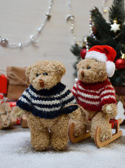 A Teddy Bear takes another one for a sledge drive on a background of a Christmas tree & boxes with Christmas presents