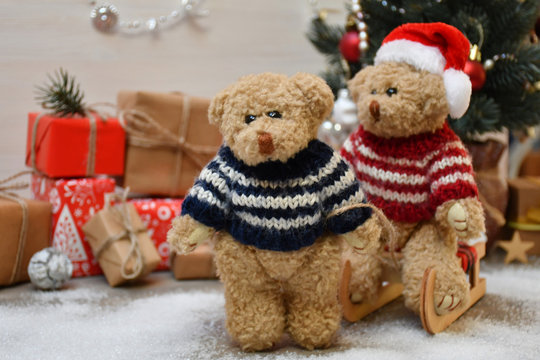 A Teddy Bear takes another one for a sledge drive on a background of a Christmas tree & boxes with Christmas presents