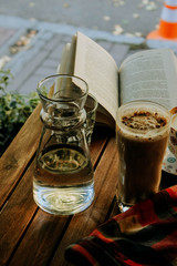 coffee, book and glass of water on a wooden table