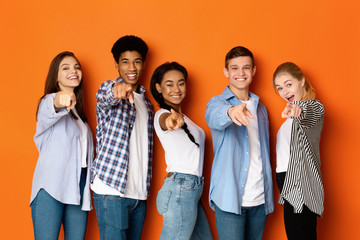 Happy teenagers pointing fingers at camera and smiling - obrazy, fototapety, plakaty