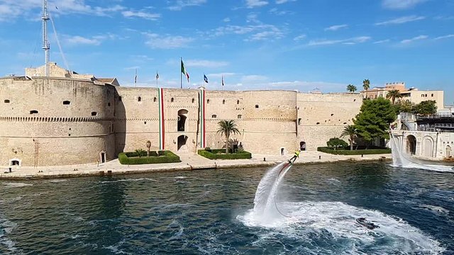 Flyboard Performance in the Taranto Canalboat in front the Aragonese Castle Decorated with Italian Flags, Souht of Italy. Slowmotion HD