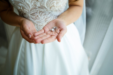 Beautiful wedding earrings in the hands of the bride on their wedding day