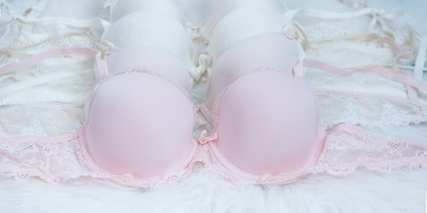 Pastel colored bras with lace on white fur. Fashionable concept of lingerie