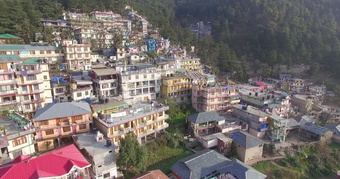 Aerial pull out away from city of Dharmasala, India, built on mountainside.