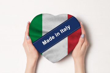 Inscription Made in Italy the flag of Italy. Female hands holding a heart shaped box. White...