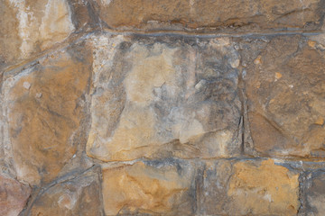 Old wall made of natural brown blocks covered with cracks. Abstract background for design and title.