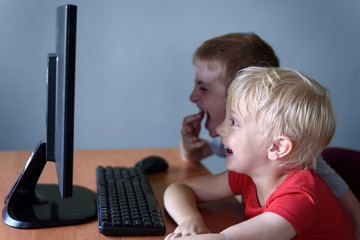 Two boys are watching something on the computer with a laugh. Children's entertainment