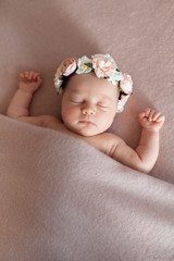 Portrait of cute sleeping newborn baby girl wearing flower headband.