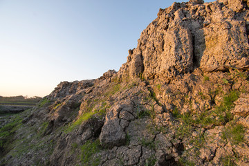 The curb erosion from storms. To indicate the layers of soil and rock.