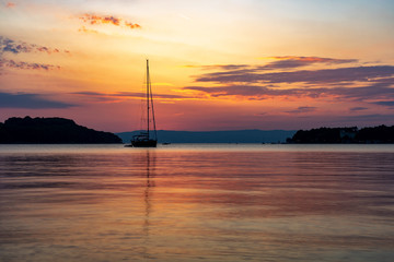 sunset on the sea with sailboats and island silhouette