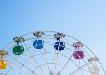 Ferris wheel with multi-colored cabs on a background of blue sky