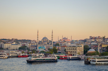 Fototapeta na wymiar Sunset sky. Tourist pleasure boats on pier in Golden Horn Bay. View of famous Hagia (Aya) Sofia Museum and the New Mosque. Popular tourist destination. Turkey, Istanbul, Bosphorus