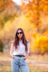 Fall concept - beautiful woman in autumn park under fall foliage