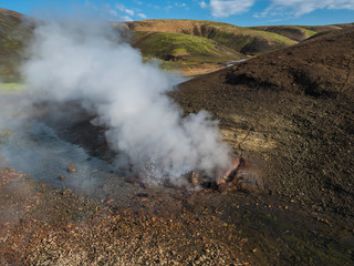 Hot spring with boiling water rising from rocks in Landmannalaugar colorful Rhyolit mountains on famous Laugavegur trek. Fjallabak Nature Reserve in Highlands of Iceland