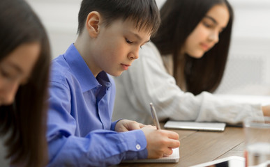 Children writing in copybooks during lesson in classroom