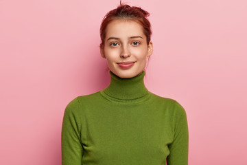 Portrait of beautiful young lady has dark combed hair, appealing appearance, wears casual green...