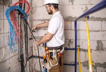 Electrician working near the Board with wires. Installation and connection of electrics.