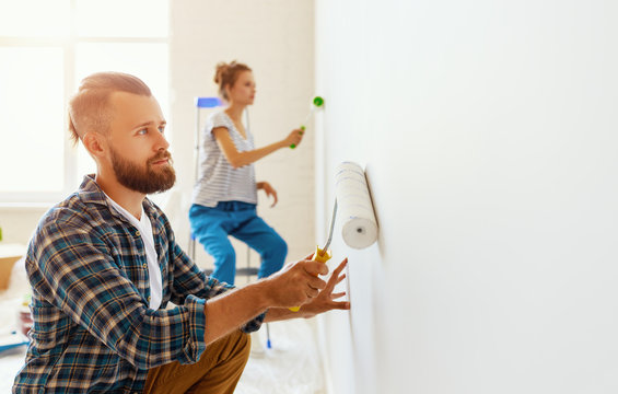 young happy couple is repairing and painting   wall at home.