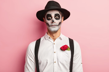 Portrait of spooky handsome guy made makeup for Halloween event, has image of vampire or ghost, red...
