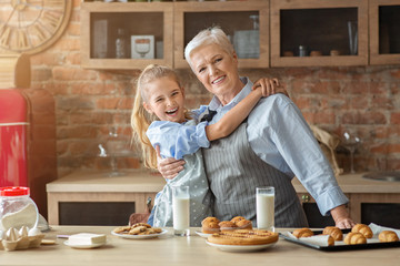 Little granddaughter hugging her happy grandmother during lunch time