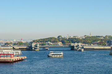 Fototapeta premium Touristic boats in Golden Horn bay and view on Galata bridge and Suleymaniye mosque. View of old city, mosque, red tile roofs and green trees. Popular destination. Turkey, Istanbul 