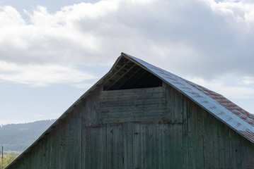 Peak of an old barn against a cloudy blue sky