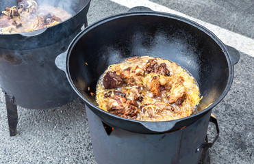 Pieces of meat cooking in a large cauldron