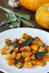 dish with pumpkin. fried chicken fillet and pumpkin cubes with sage (chips from sage). a dish on the table on a sunny day. autumn dish with pumpkin.