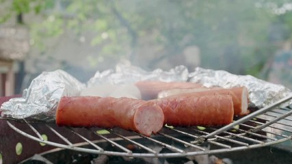 Close Up to Barbecue Grill with Roasted Meat Sausages and Food in Foil Grilling on Coal at Outdoors Picnic BBQ Party in Summer Weekend. 4K Static Background Shot